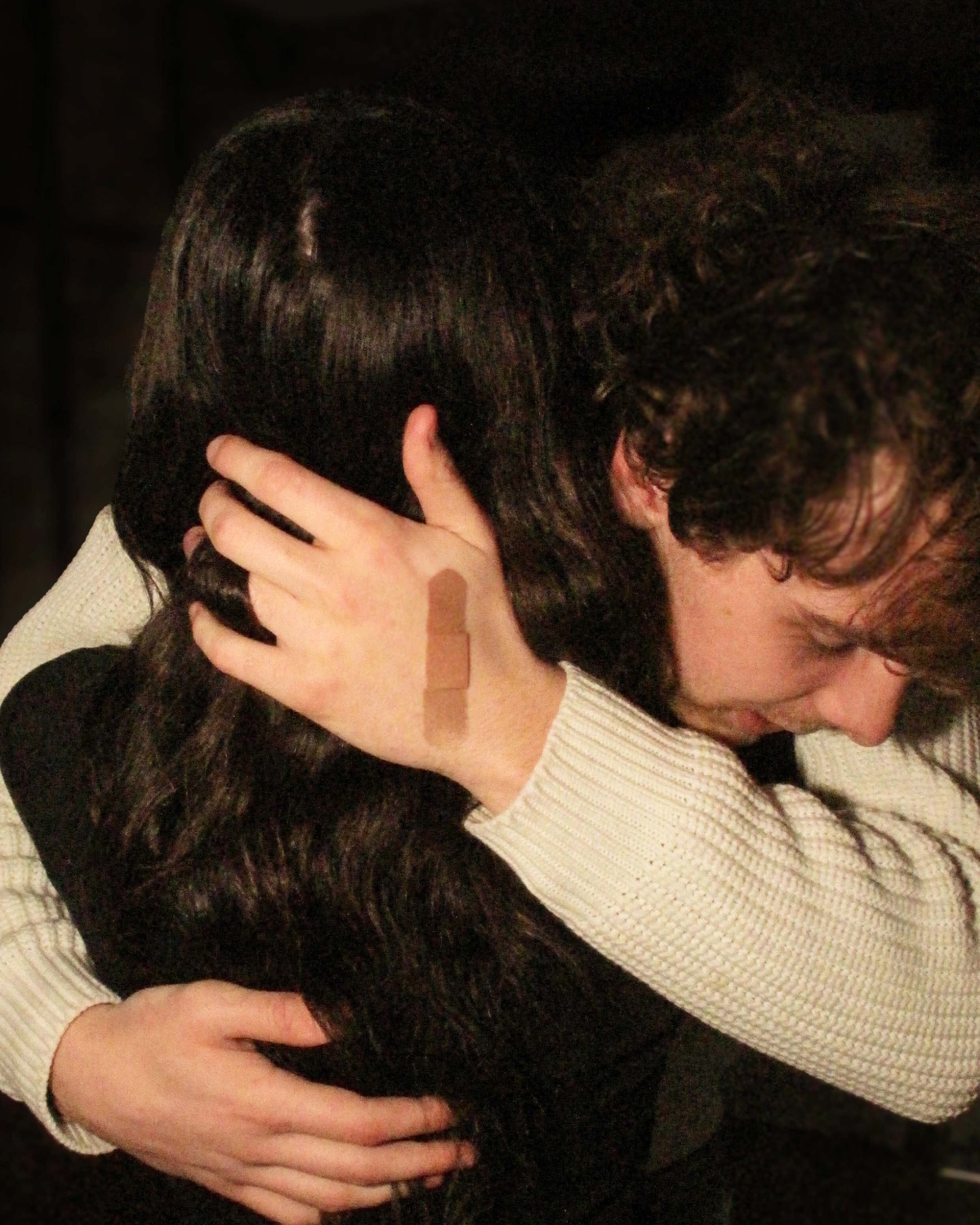 Two people embracing, a bandage across one hand