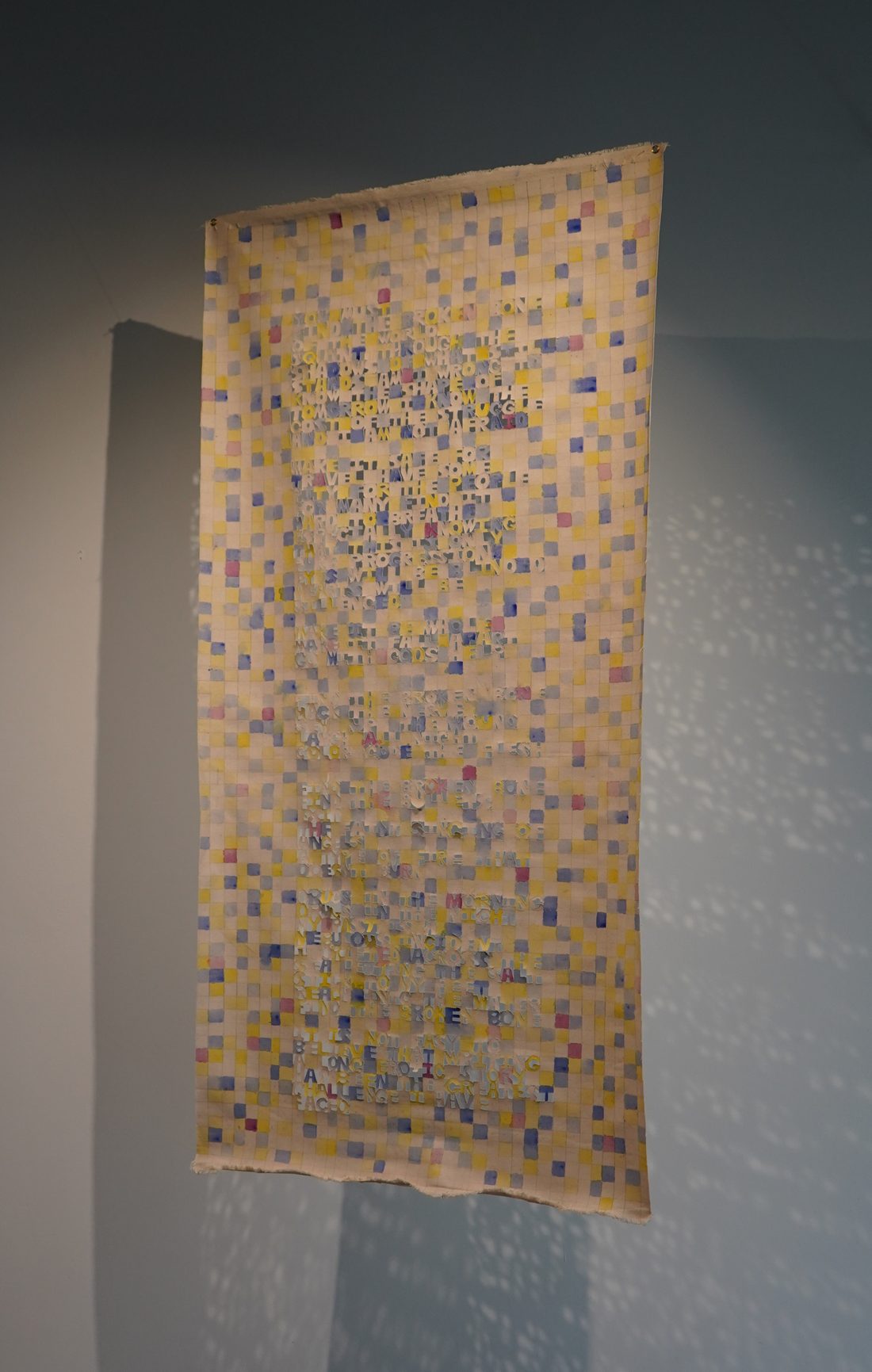 Hanging textile with cut-letter poem, installation view