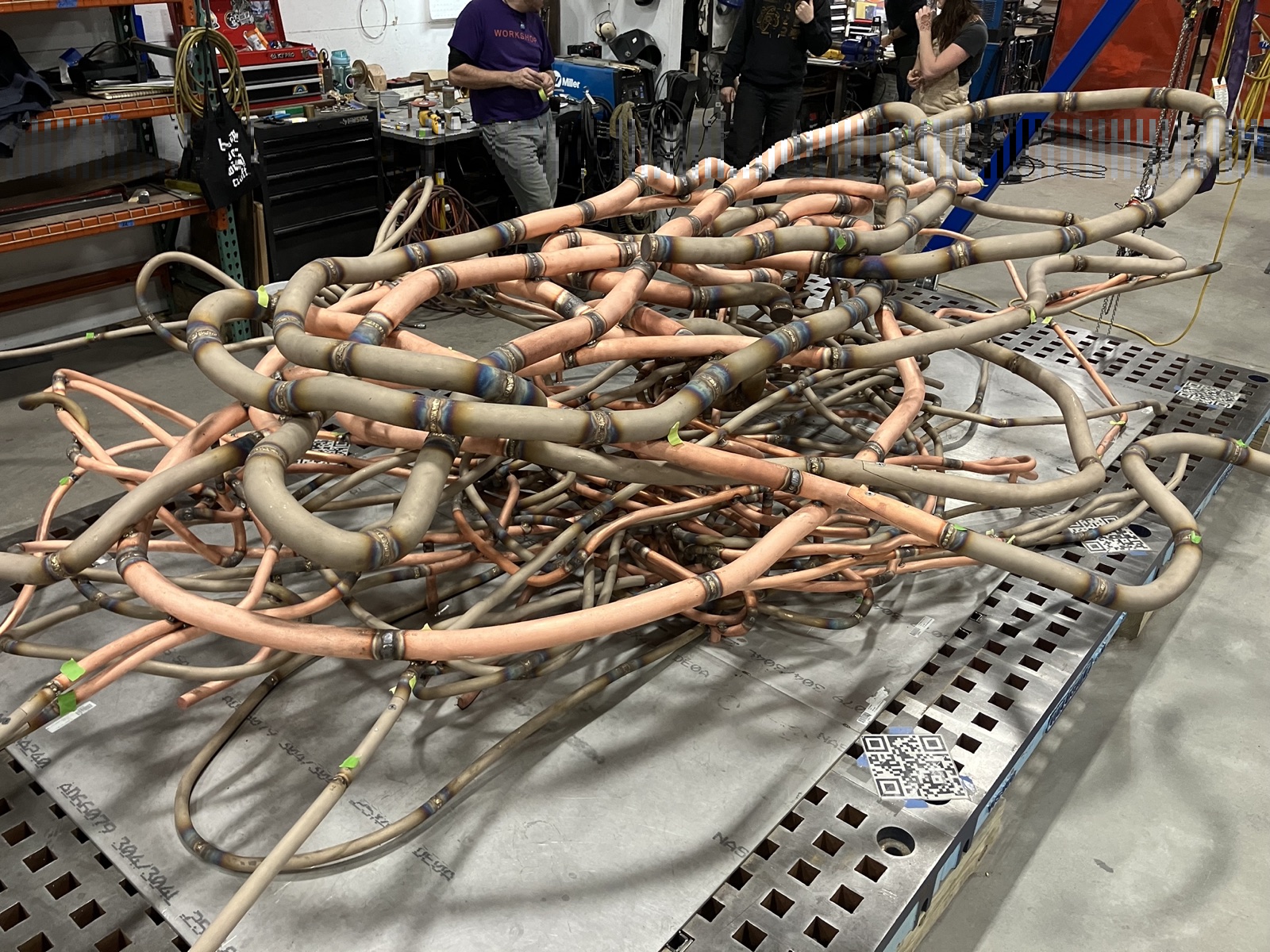 Bent copper and steel tubing laid out across a fabrication shop floor